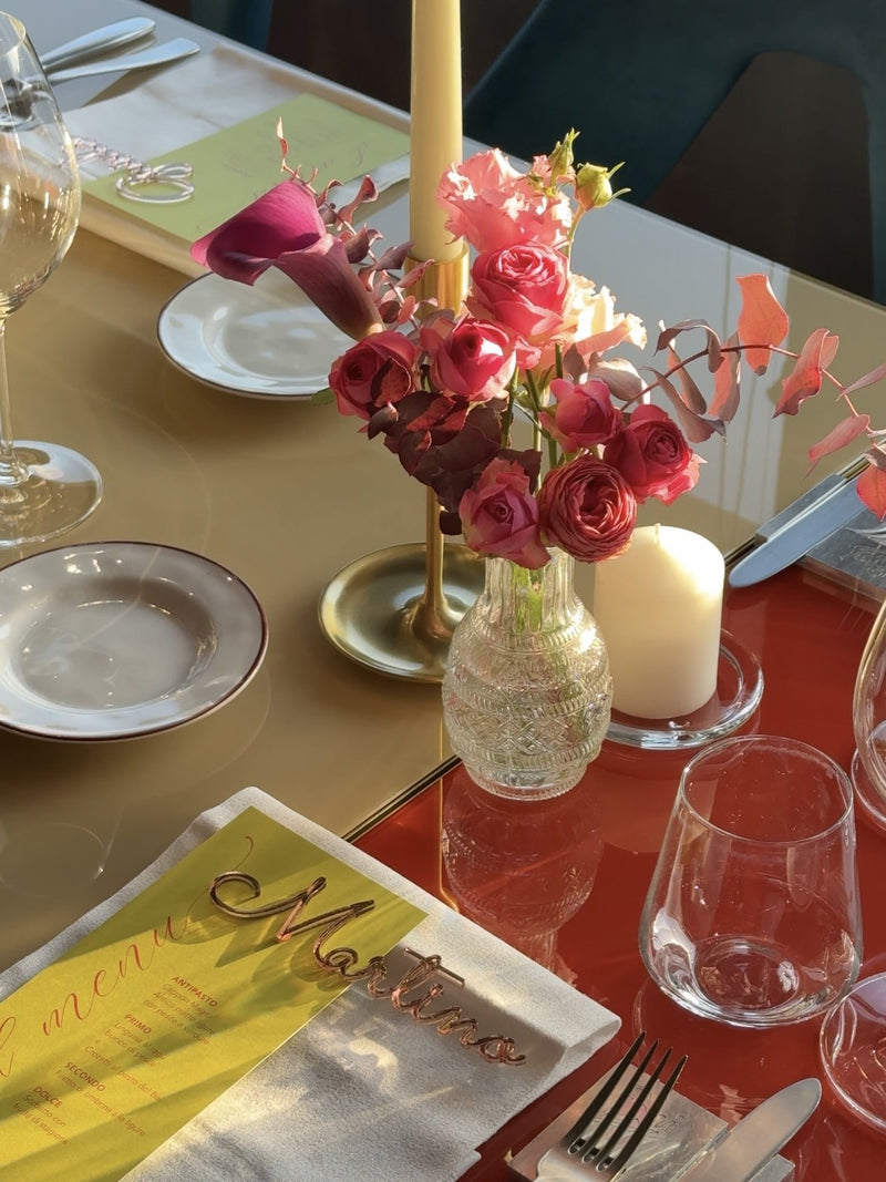 Centrotavola di rose e calla in vaso di vetro accanto al segnaposto e al menù