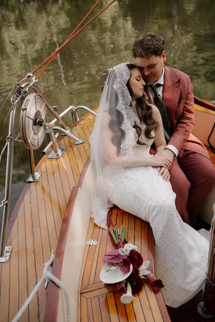 Sposi su una barca in legno con il bouquet della sposa