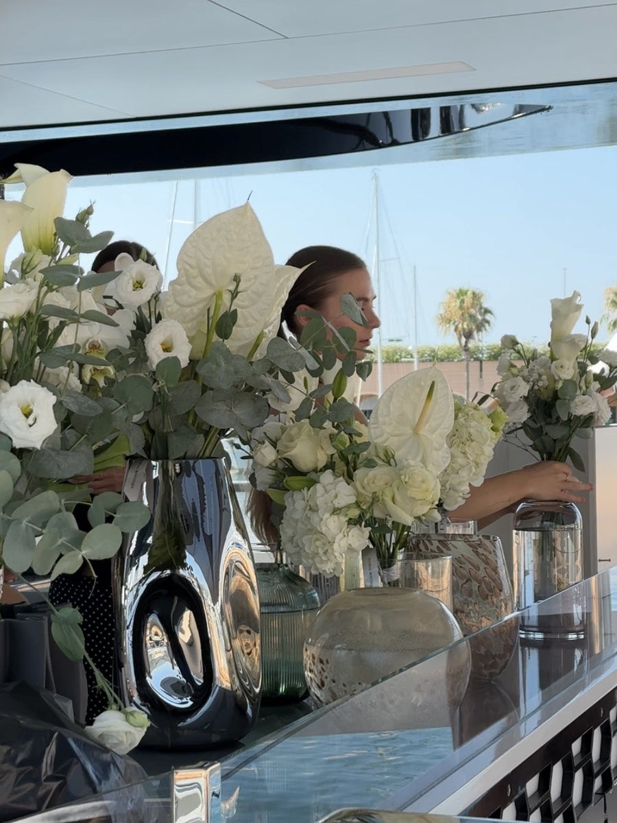 Composizioni bianche con anthurium e calle in vasi di vetro sul bar dello yacht